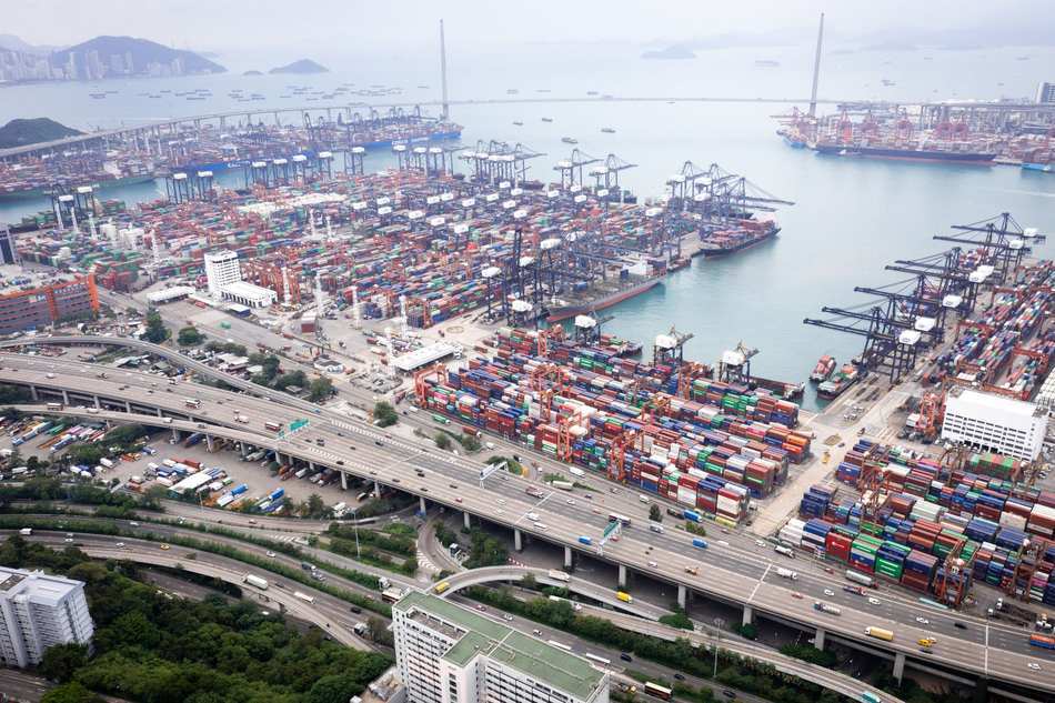 Aerial view of a busy container port with terminals, gantry cranes and stacked boxes