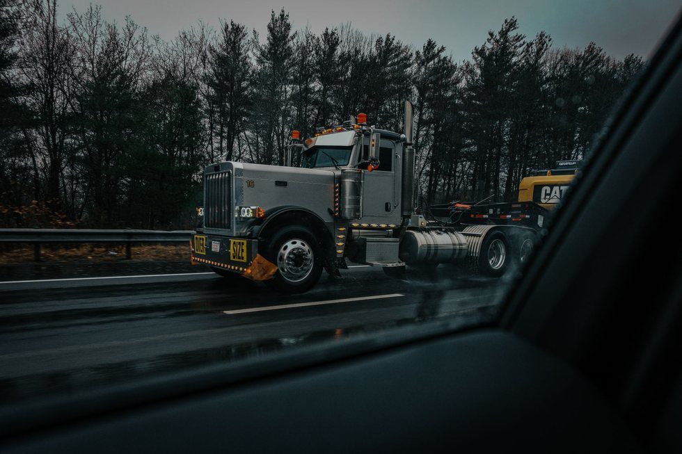 Wide over-size load truck travelling on an open highway under an overcast sky