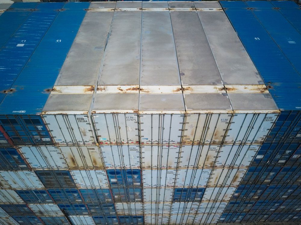 Aerial view of stacked blue and white shipping containers at a container terminal
