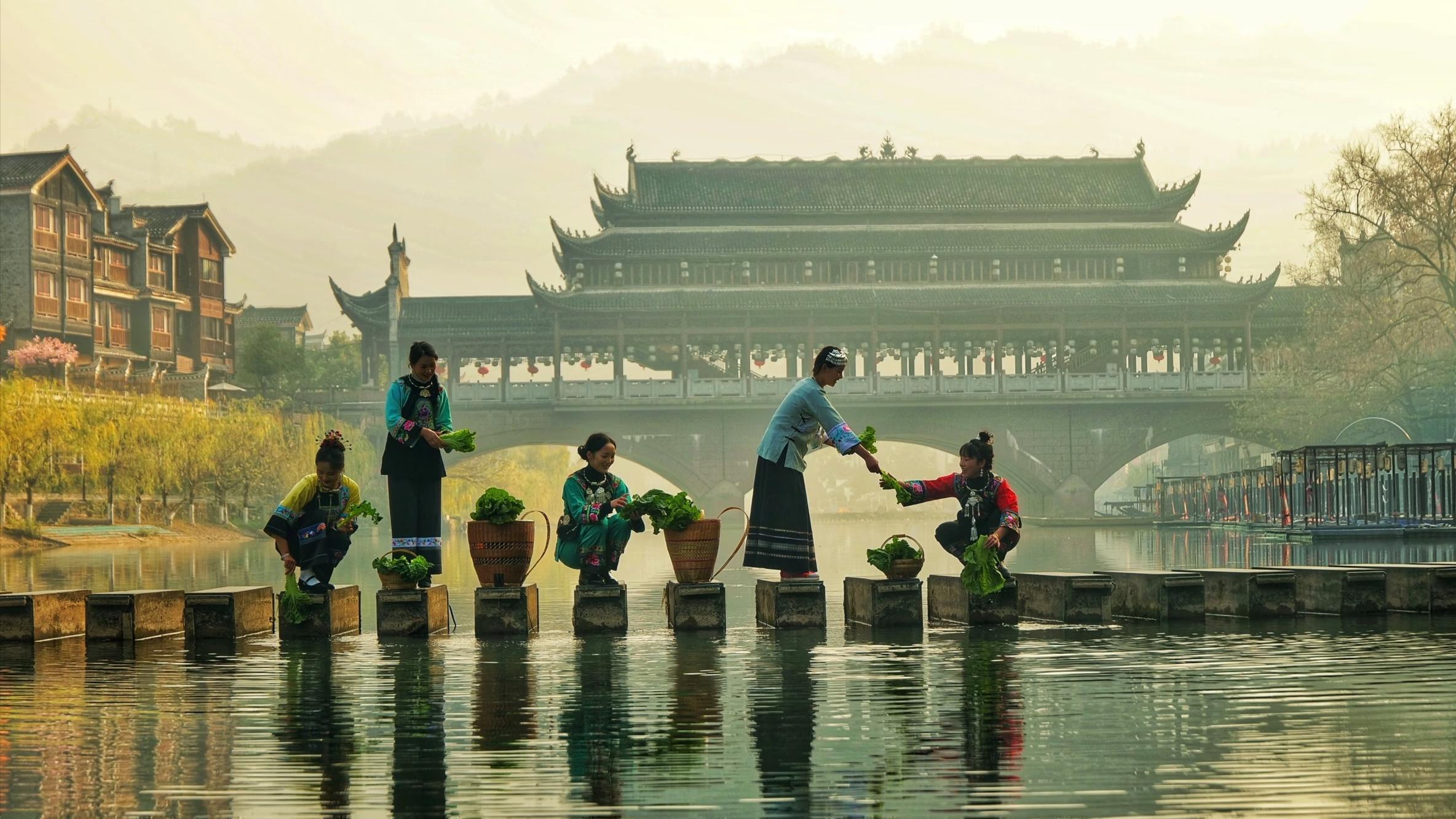 Woman washing clothes by stilted houses (diaojiaolou) in western Hunan, China