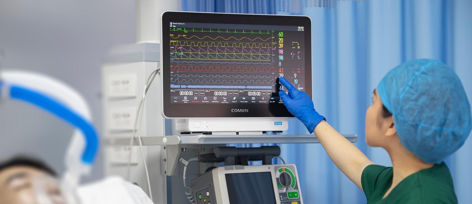 Nurse operating a patient monitoring touch display at bedside