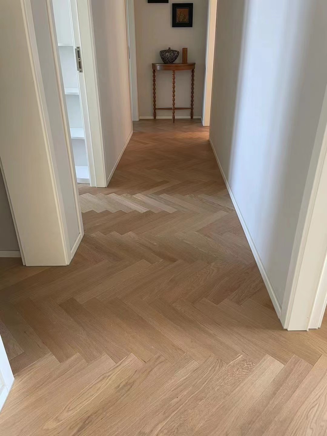 Light natural oak herringbone engineered wood flooring installed in a luxury Sydney Harbour condominium with modern French interior styling and bright natural lighting.