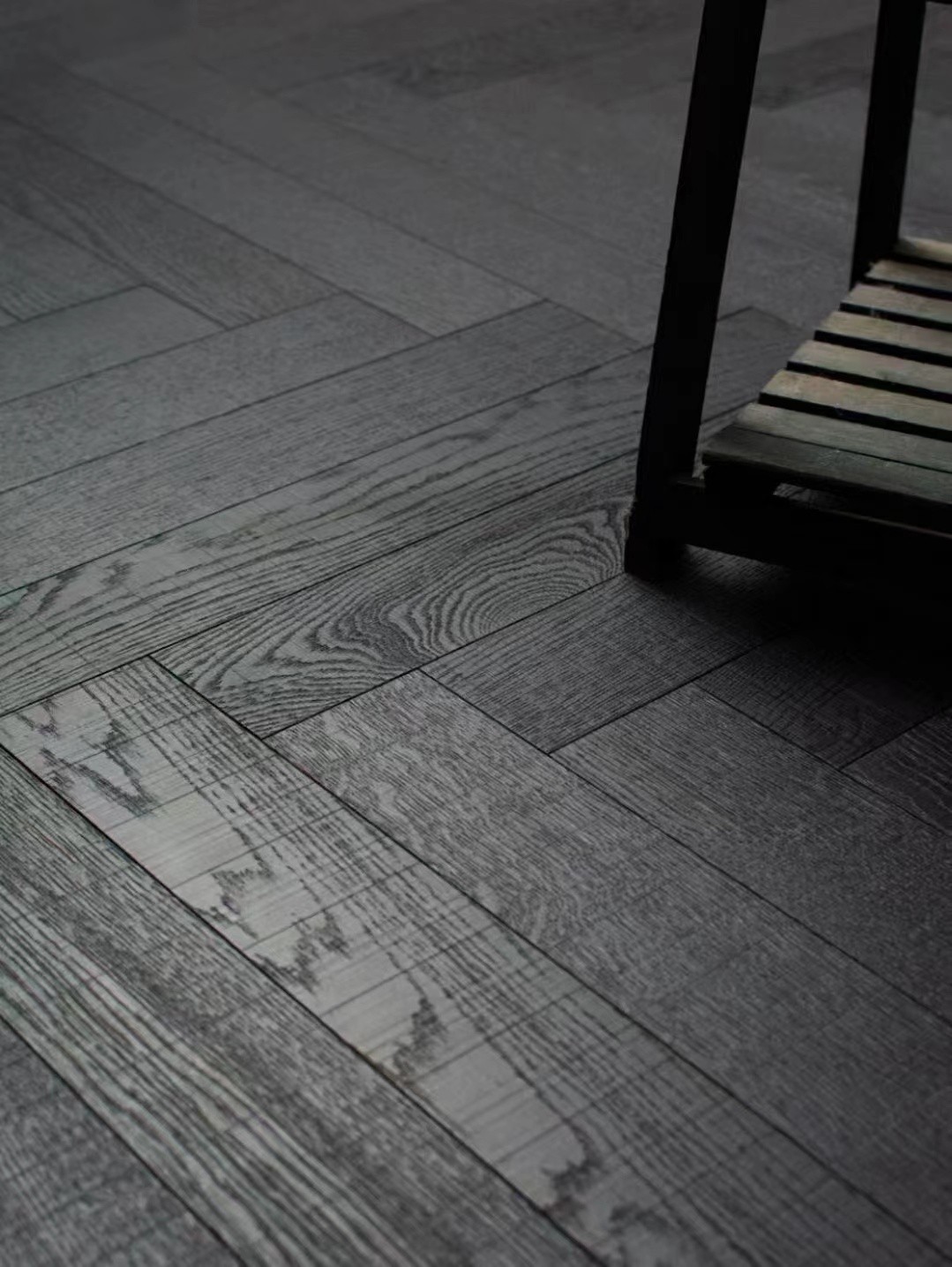 Dark wide herringbone engineered oak flooring installed in a modern luxury penthouse in Dubai with panoramic skyline views and minimalist interior styling.