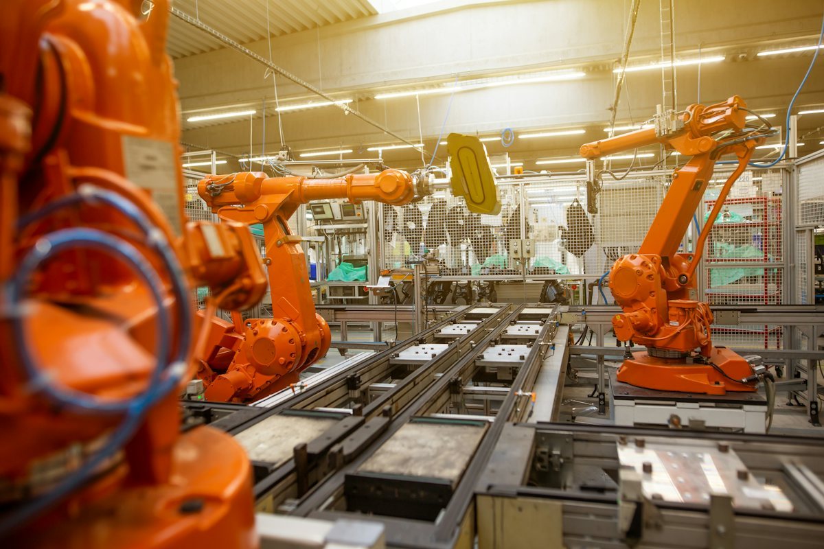 Multiple industrial robot arms with visible joint structures on a production line.