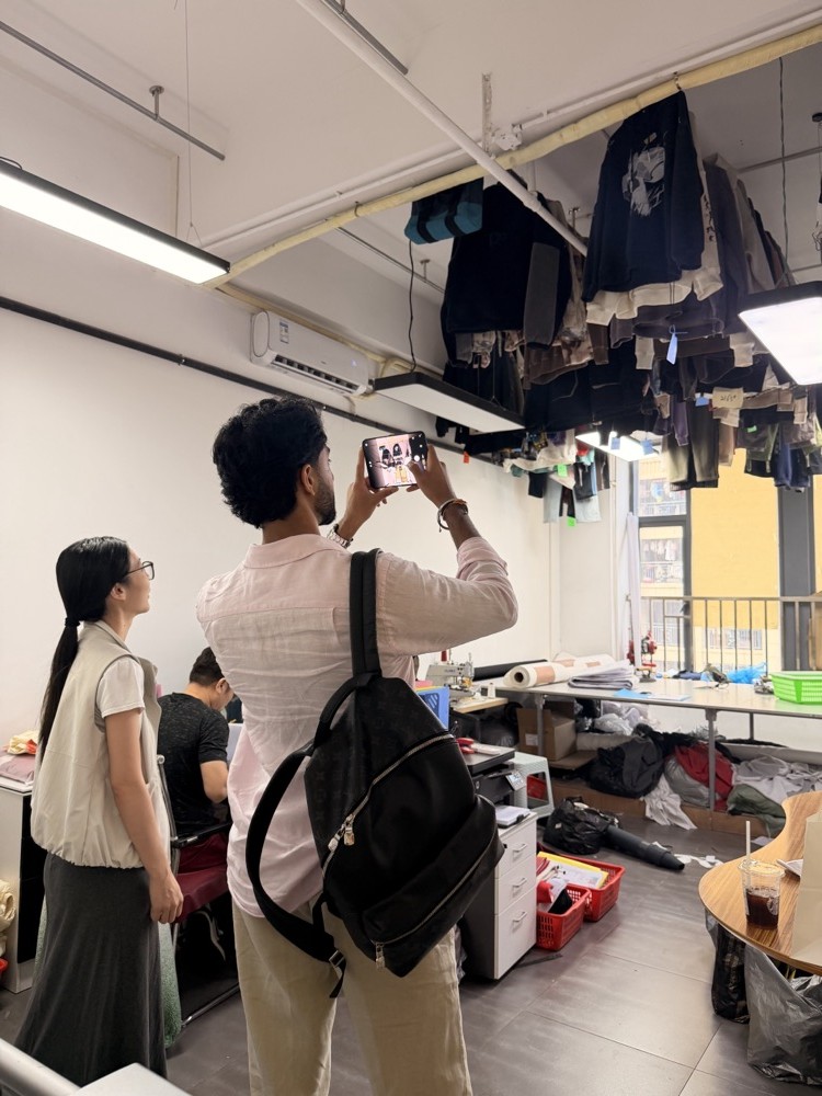 UK brand client photographing hanging garment samples during a factory visit in Dongguan
