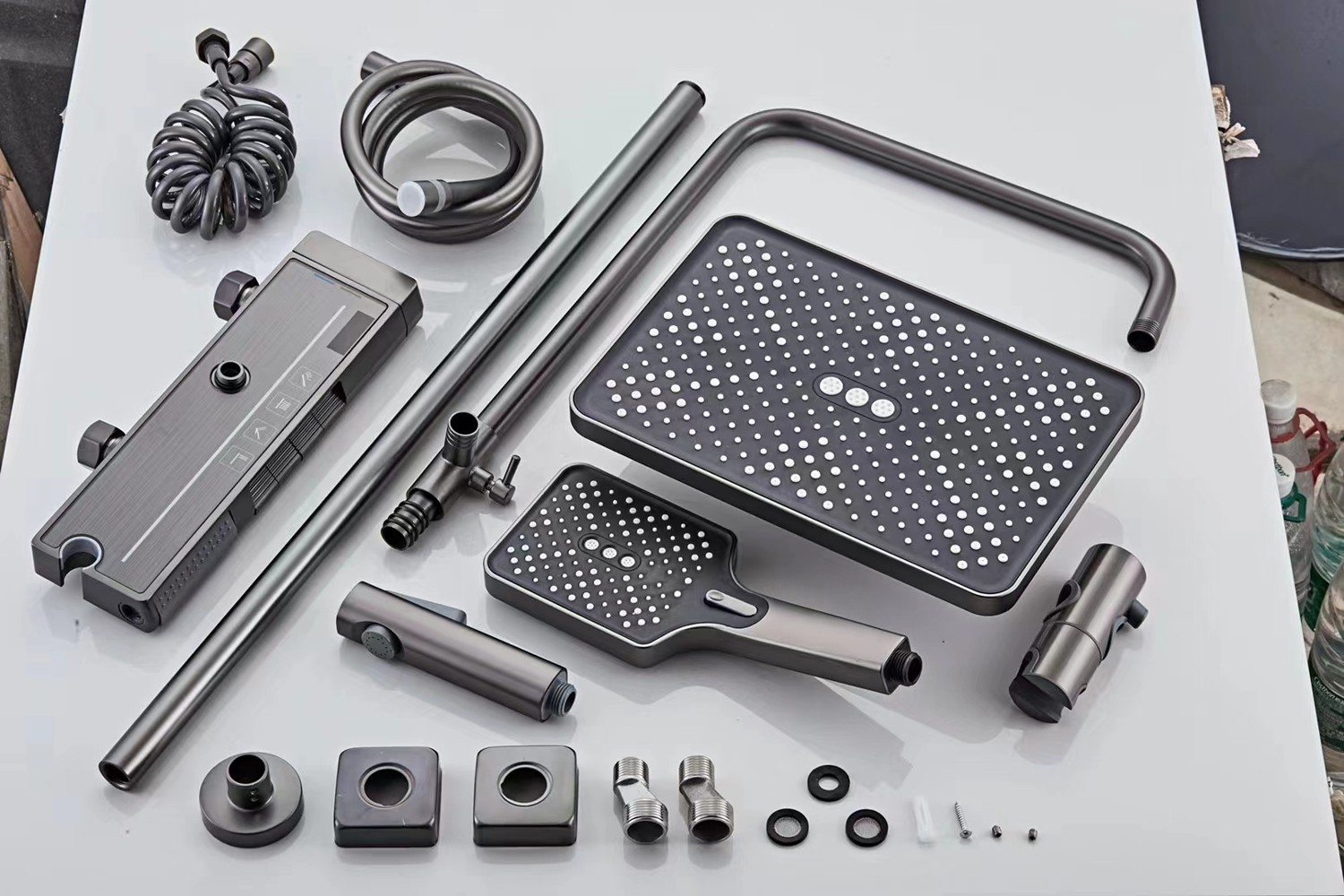 Exploded view of an exposed shower set laid out with all components including valve body, rain head, hand shower, hose, riser bar and fittings