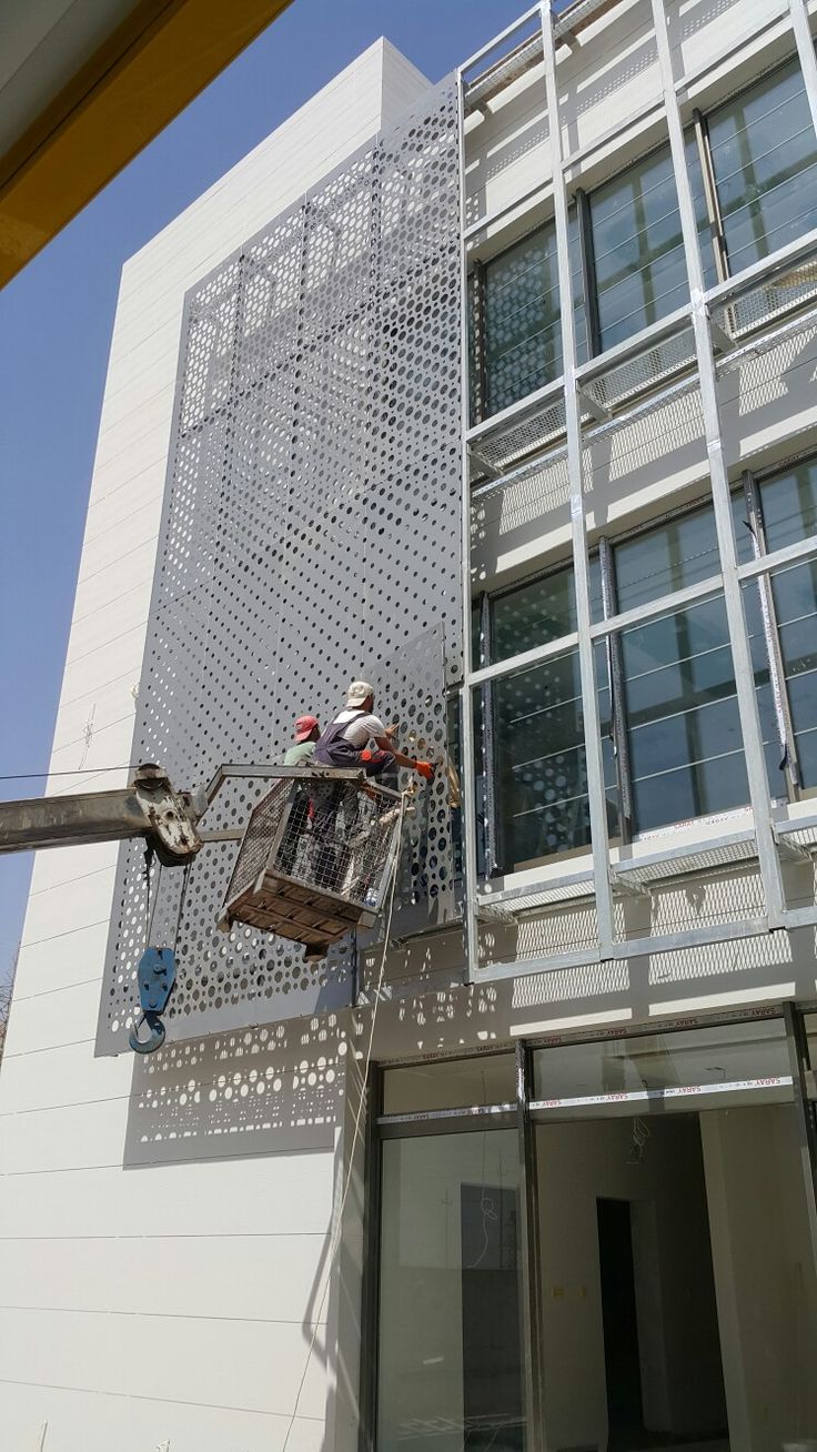 Perforated stainless steel screen panels being installed on site with a lifting platform