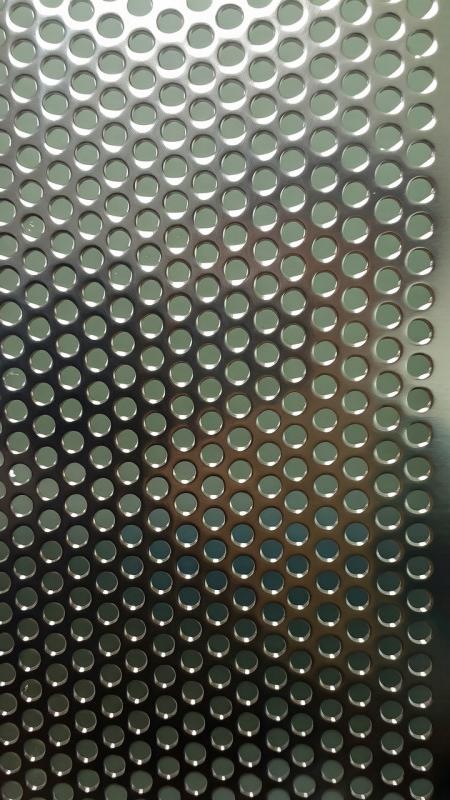 Round-hole perforated stainless steel at a raking angle, showing hole depth and density