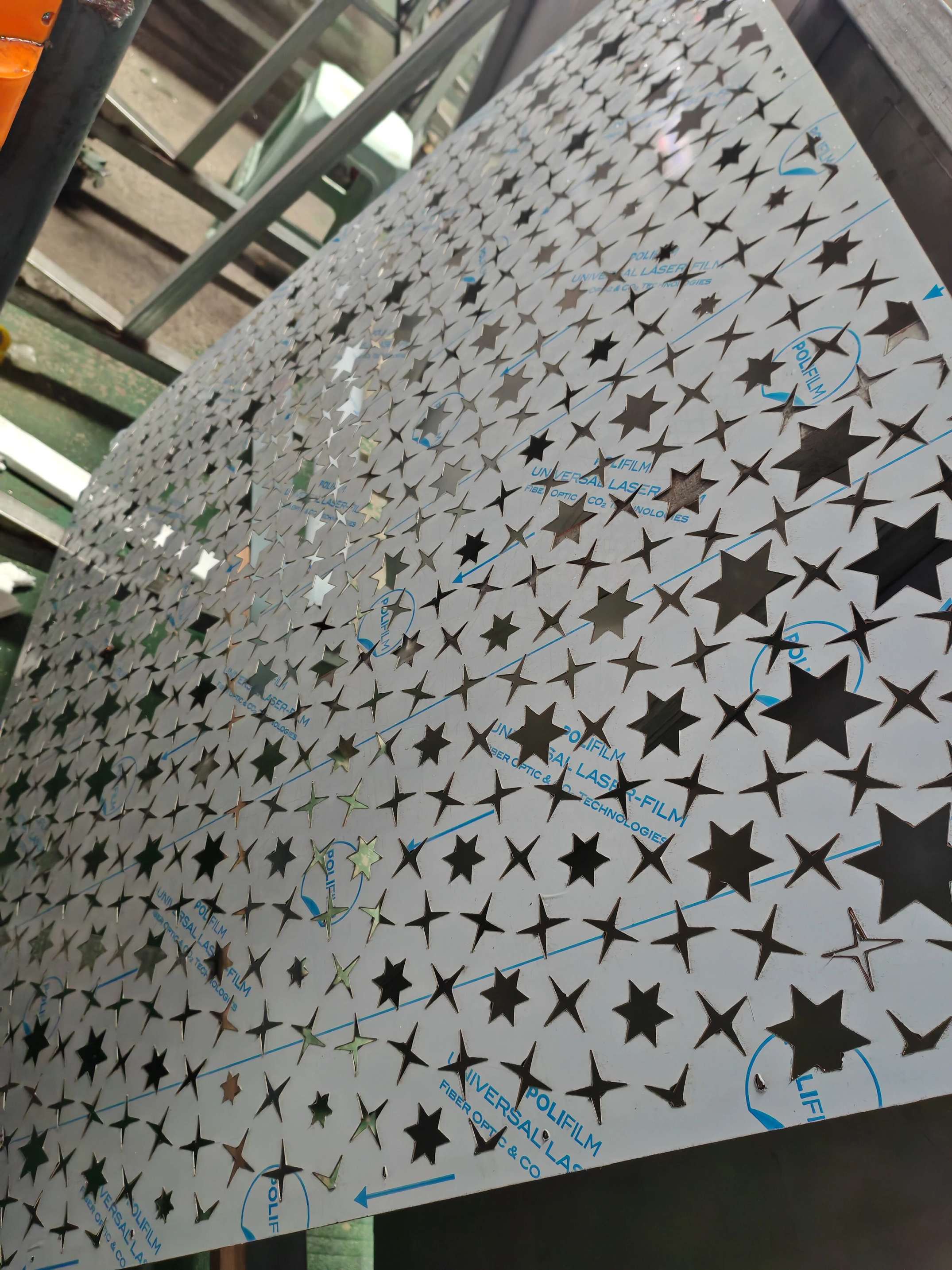 Custom star-pattern perforated stainless steel sheet in production with protective film