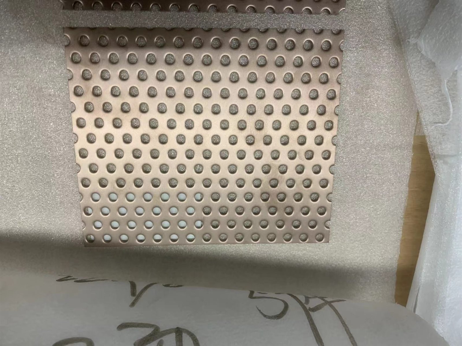 Perforated stainless steel sample panel with finish label