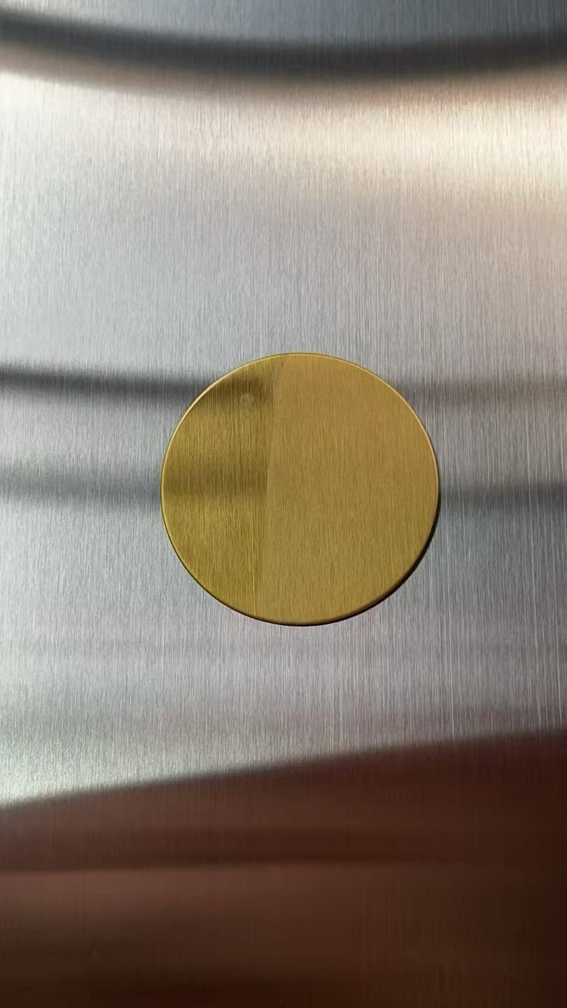 Gold brushed sample disc checked against the production brushed stainless steel surface