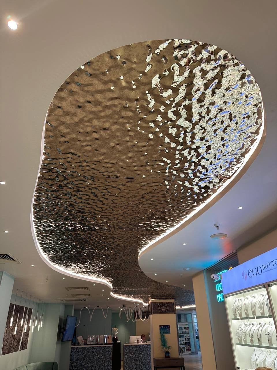 Custom-formed curved stainless steel ceiling panel with a folded backlit edge