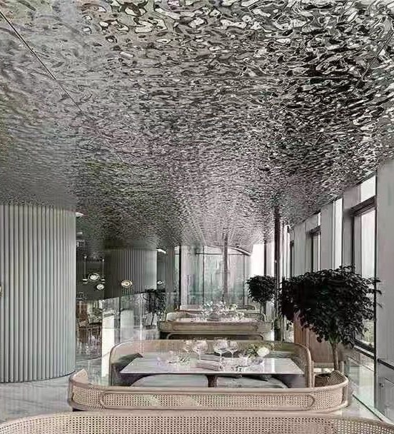 Formed ripple stainless steel ceiling with raking light revealing three-dimensional relief