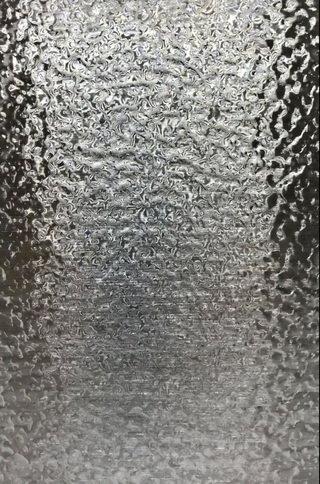 Water ripple embossed stainless steel sample plate photographed flat in studio light