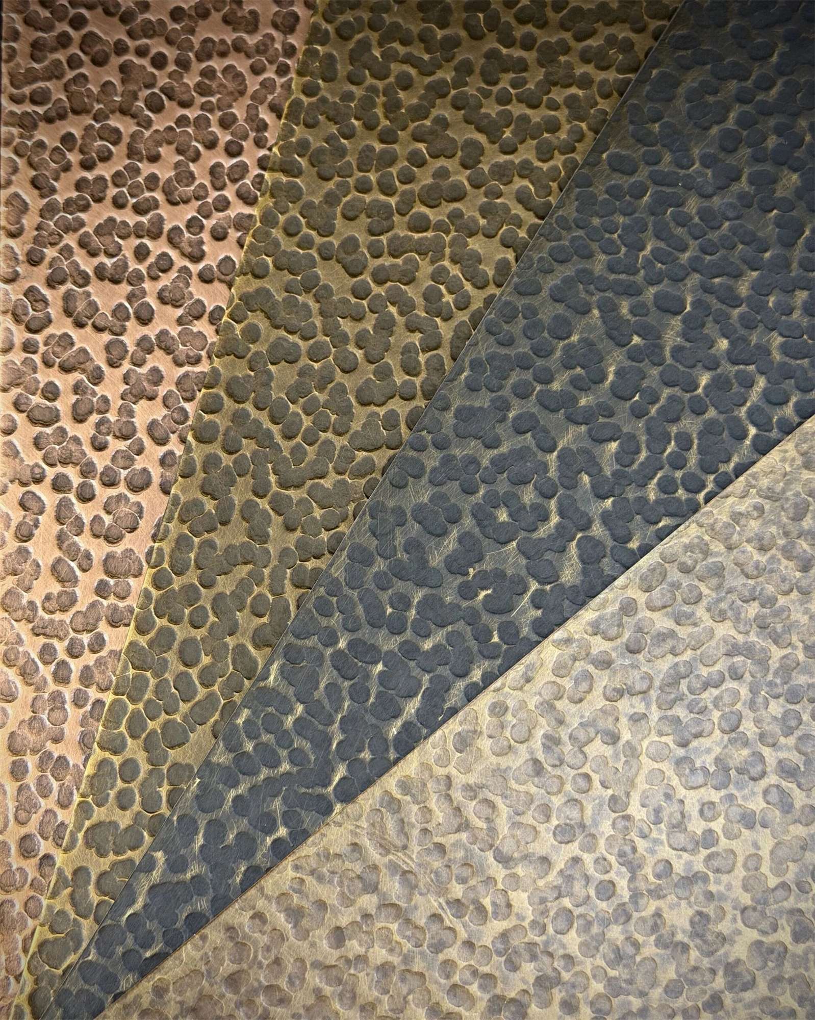 Hammered stainless steel sample plate showing pebble dimple relief across finish bands