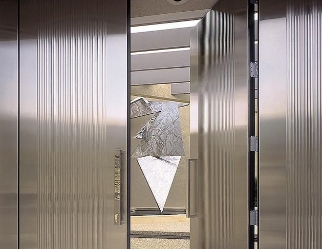 Fluted stainless steel cladding across lift doors and lobby walls
