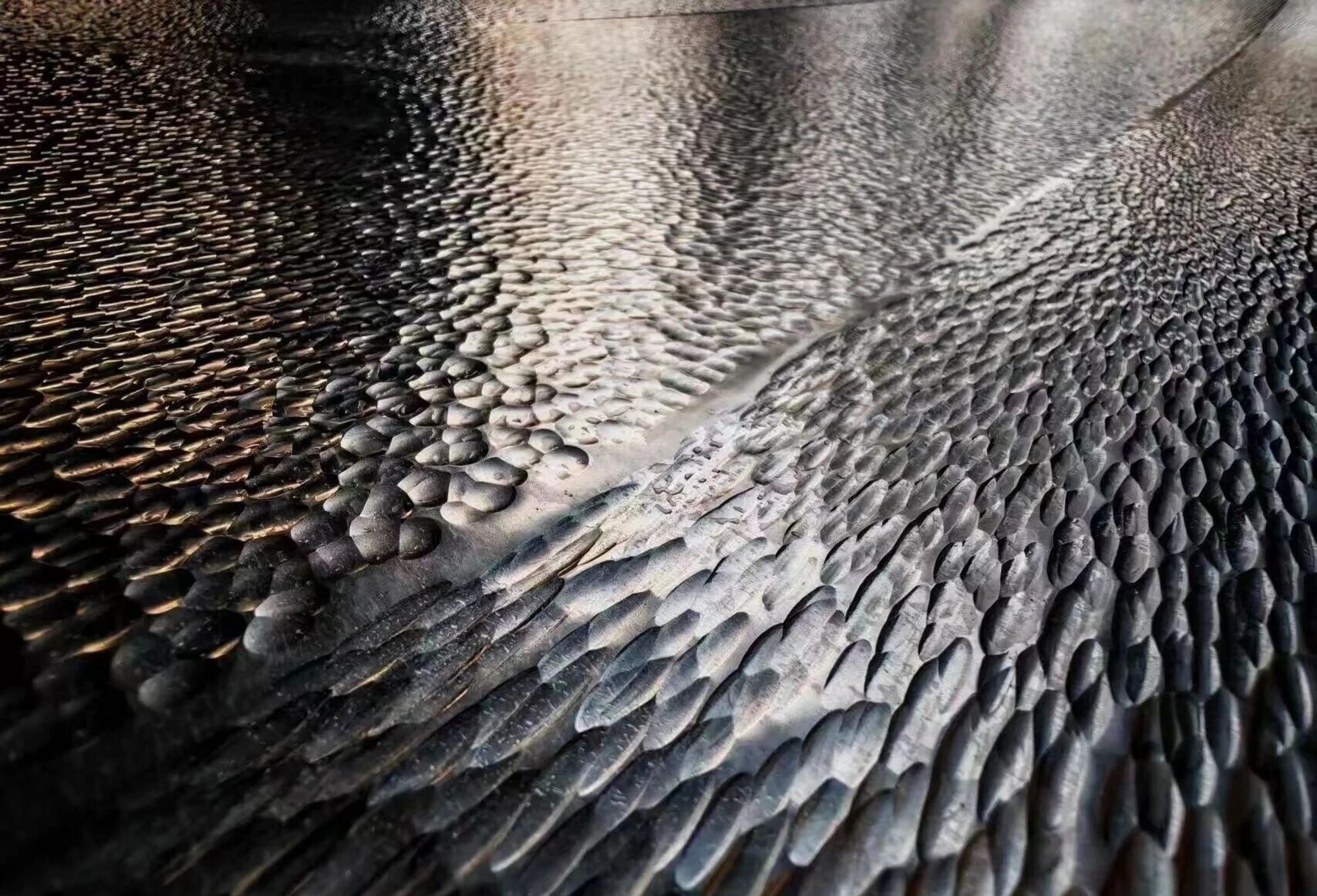 Deep organic embossed relief on a bespoke formed stainless steel element