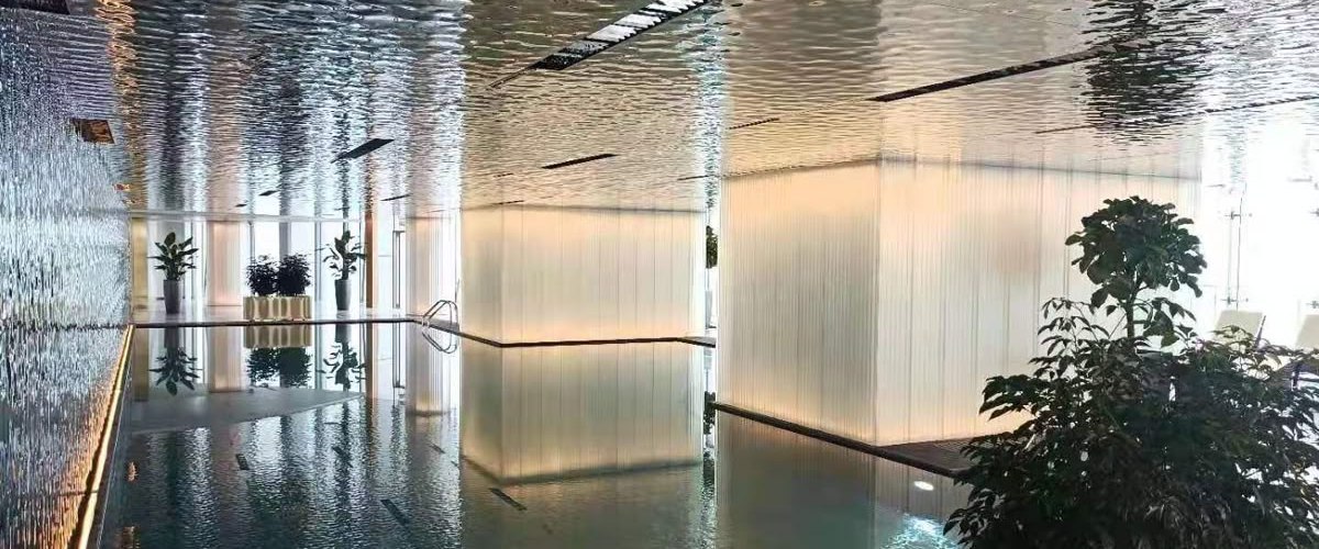 Mirrored water ripple stainless steel walls reflecting a bright lobby corridor in natural silver