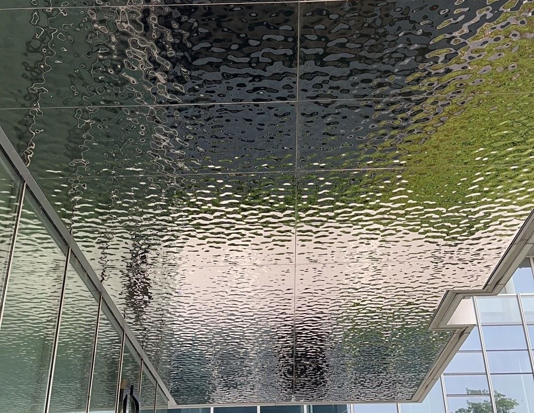Water ripple mirror cladding across a lobby with glass and daylight reflections