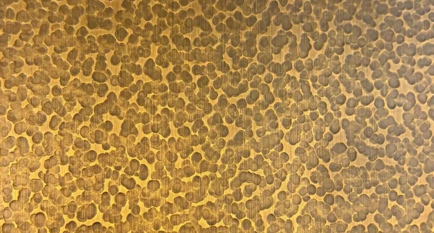 Hammered stainless steel surface with irregular pebble dimple relief