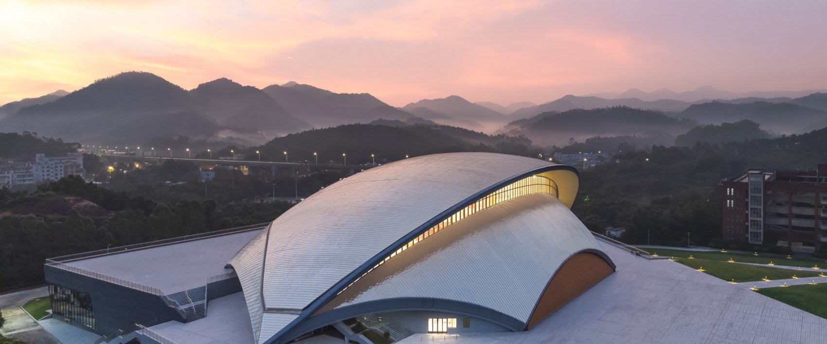 Curved stainless steel roof reflecting the sky above an architectural building