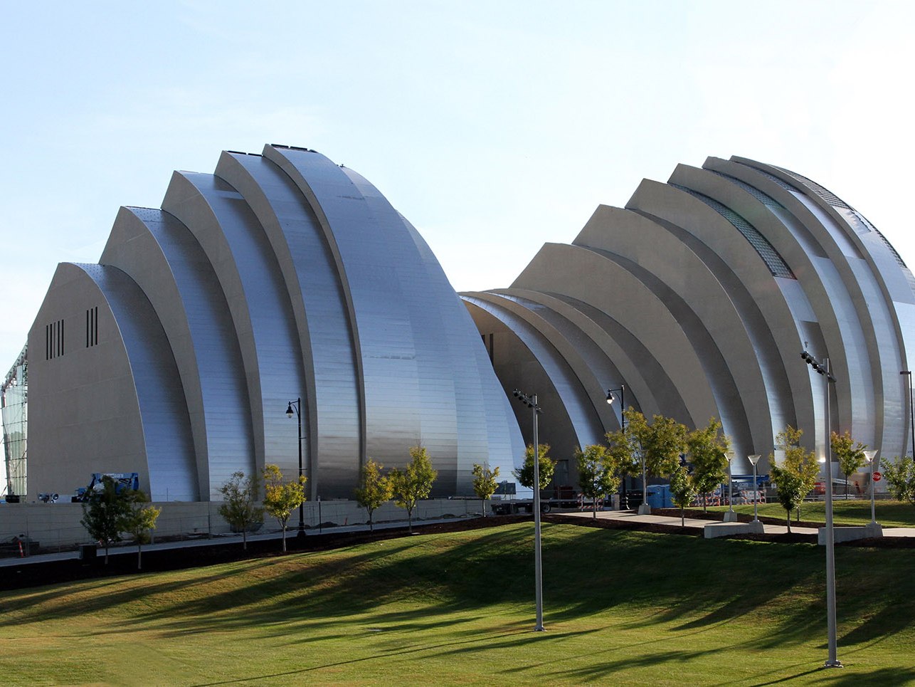 Reflective stainless steel roof shells catching light above a performing arts centre
