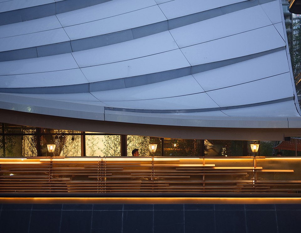 Wide stainless steel roof plane over a hospitality building at dusk