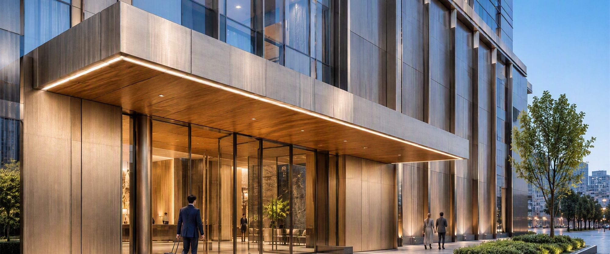 Hotel entrance canopy in champagne cladding at blue hour with warm interior light