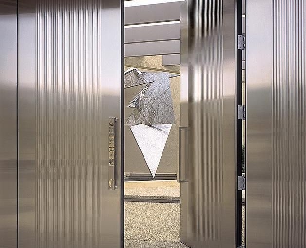 Stainless steel wall cladding meeting a fluted portal at close range