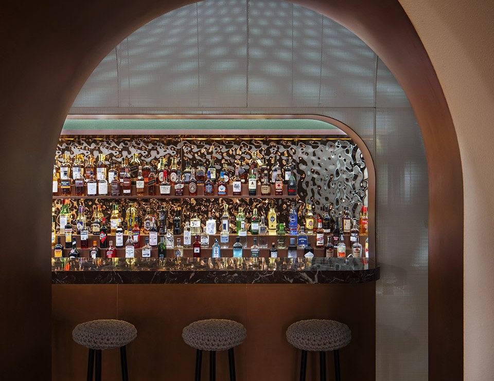 Warm textured stainless steel wall behind a hospitality bar counter