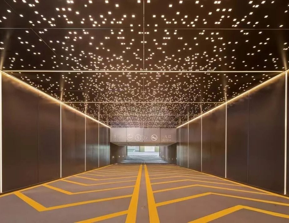 Patterned stainless steel ceiling and wall lining along a concourse corridor
