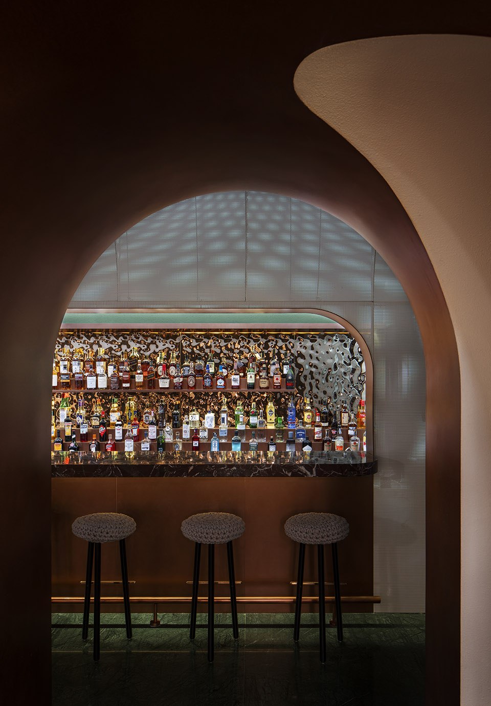 Metal-framed feature cabinet with a backlit bottle display under a textured metal ceiling