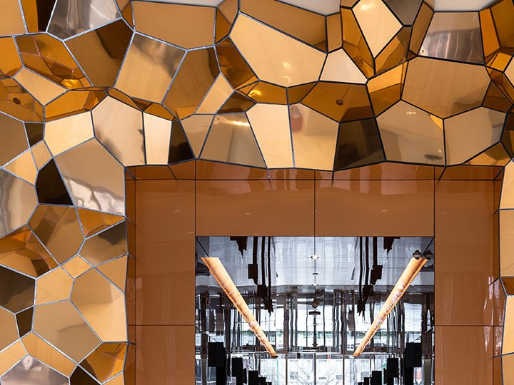 Project-specific faceted PVD gold stainless steel canopy where geometry becomes part of the space