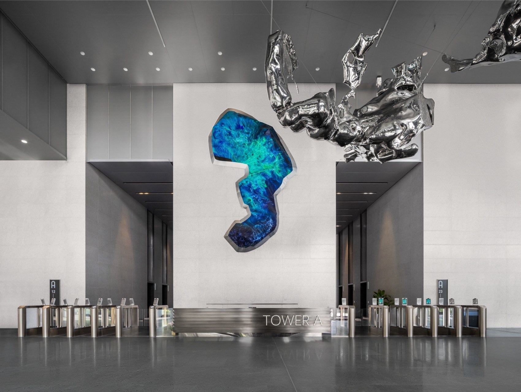 Suspended mirror-polished stainless steel sculpture in a large interior lobby