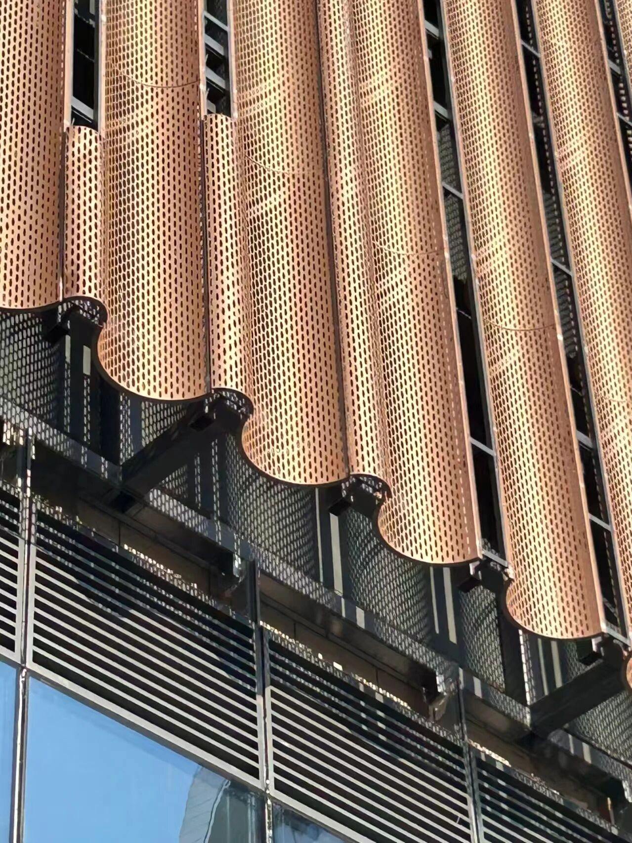 Facade clad in warm bronze-toned PVD stainless steel louvres