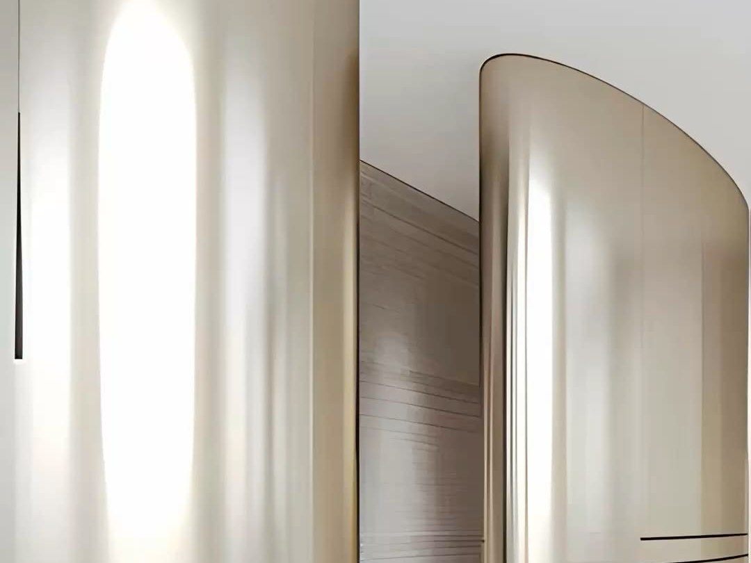 Large curved stainless steel wall panels in a bright public interior