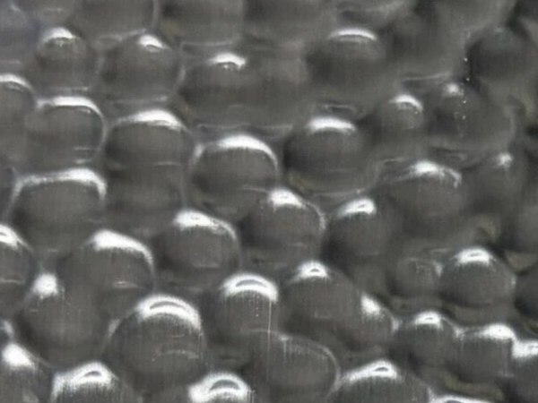 Extreme close-up of hammered stainless steel showing the physical relief of each raised and recessed area