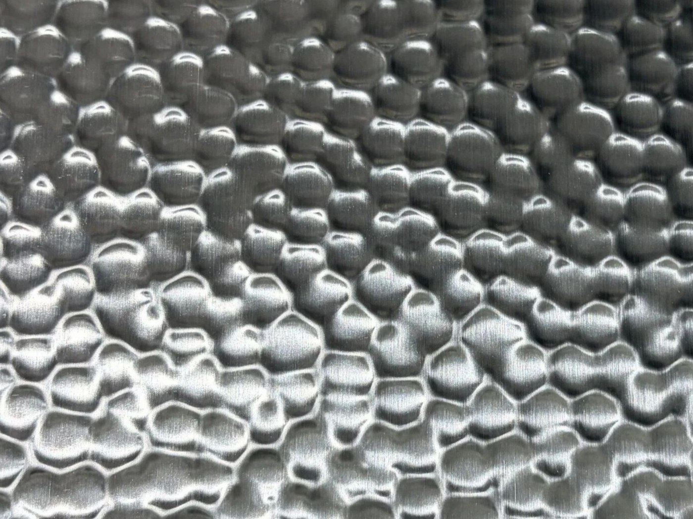 A full hammered stainless steel sheet where individual relief reads as an overall material texture