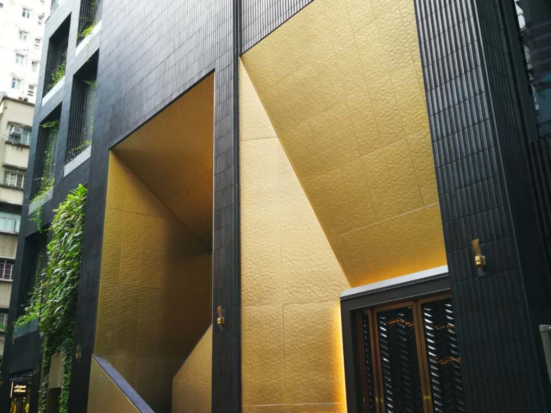 An entrance portal clad in hammered stainless steel creating a textured arrival