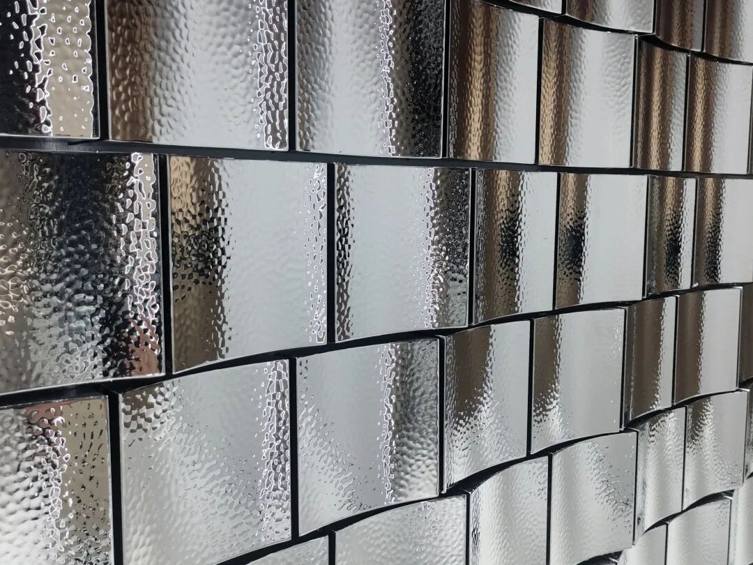 Hammered stainless steel cladding reading at architectural scale inside a quiet interior