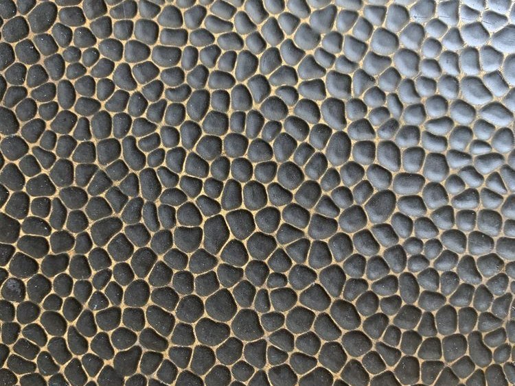 Fragmented highlights and shadows where the hammered surface breaks up its own reflection