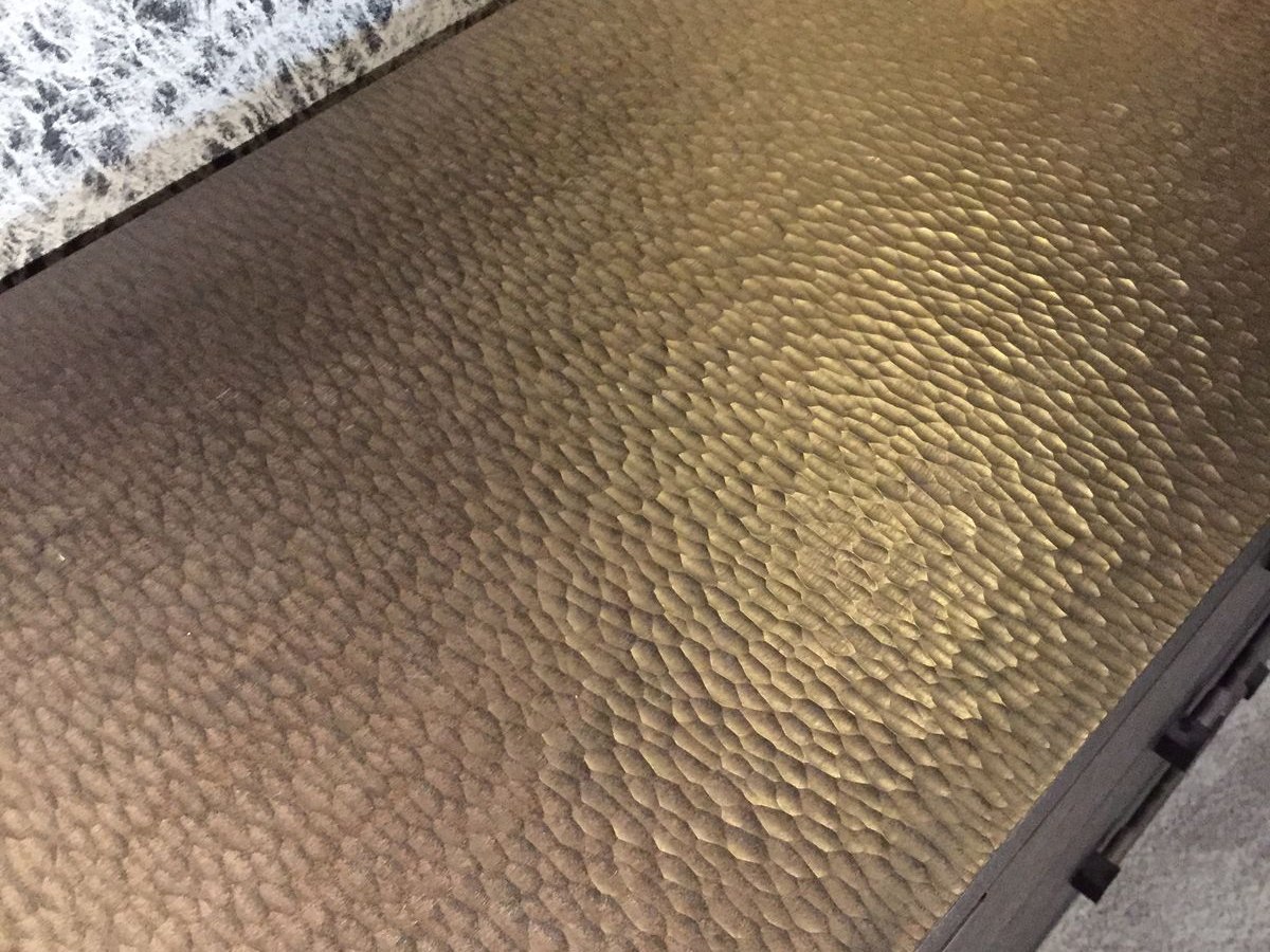 The same hammered surface seen from a distance, where perception shifts to broader light and shadow