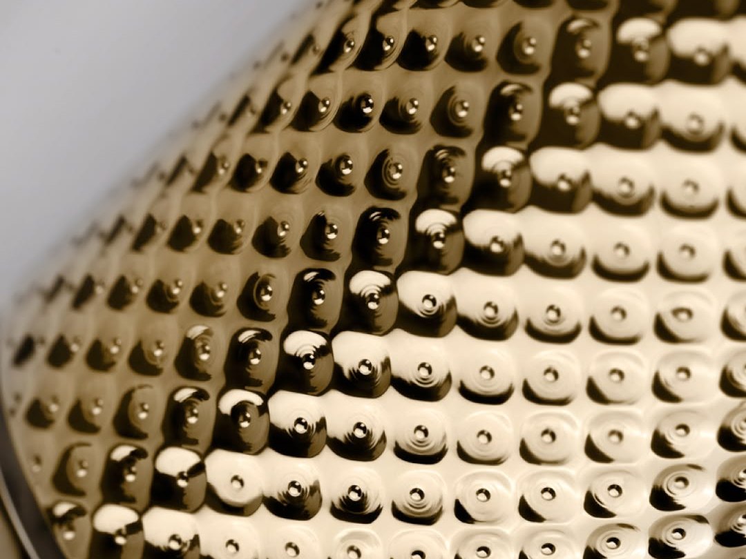 Irregular rhythm across a champagne hammered stainless steel surface that never repeats as a graphic pattern