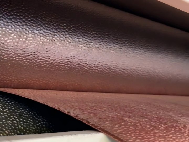 A stainless steel sheet passing over the rollers as the embossed hammered pattern is rolled into the surface