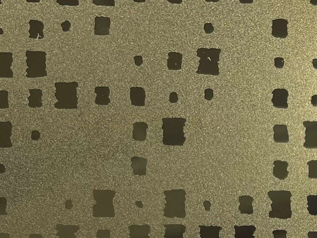 Etched stainless steel with a grid of repeated geometry forming a structured pattern