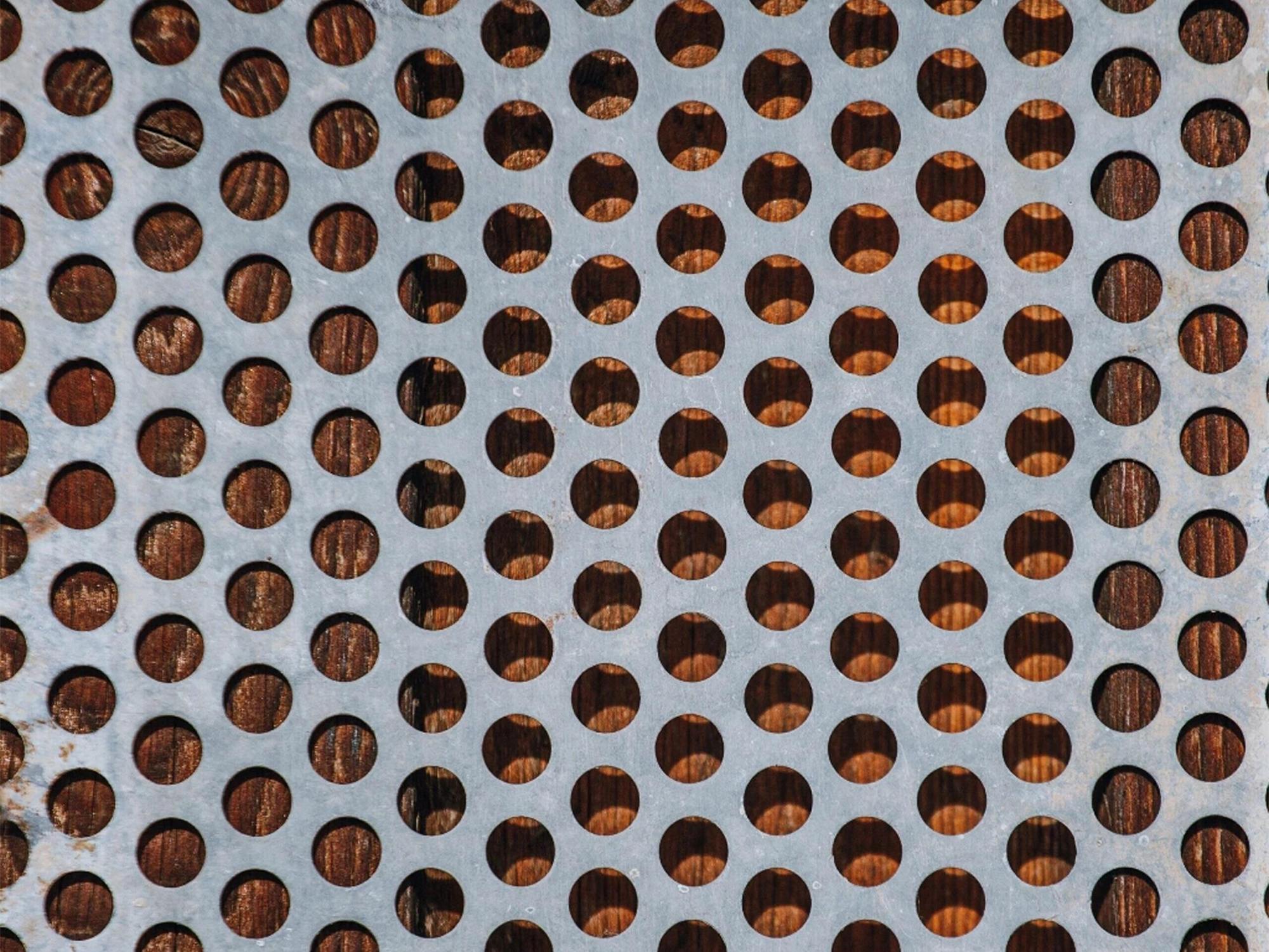 A perforated stainless steel panel where the pattern is created by openings through the sheet