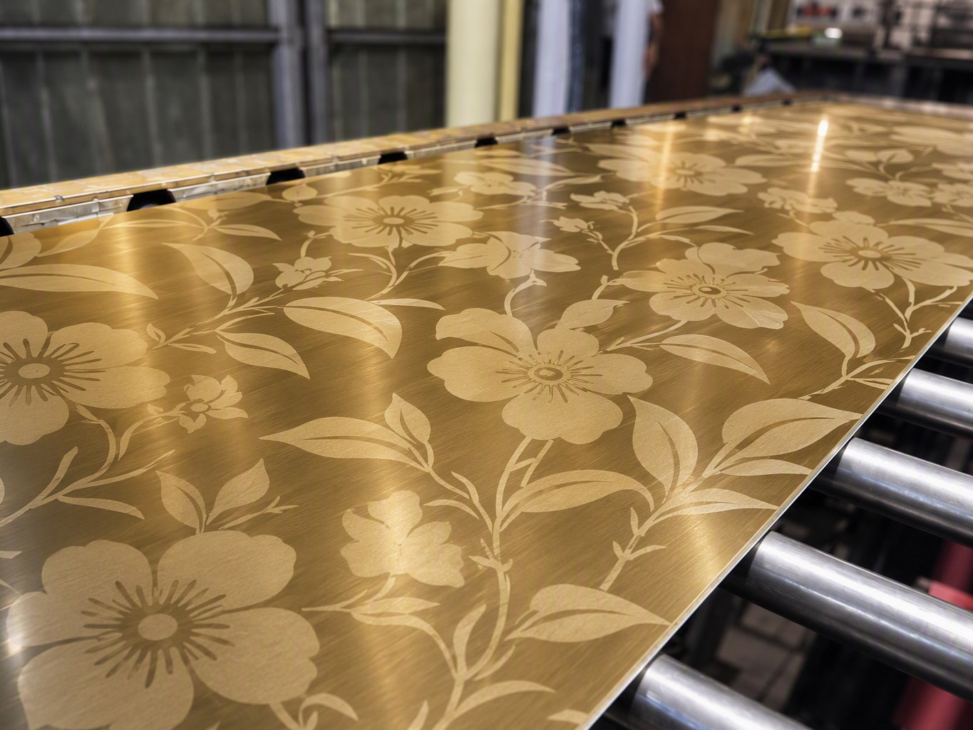 The same floral etched pattern repeated across a complete stainless steel sheet on the production line