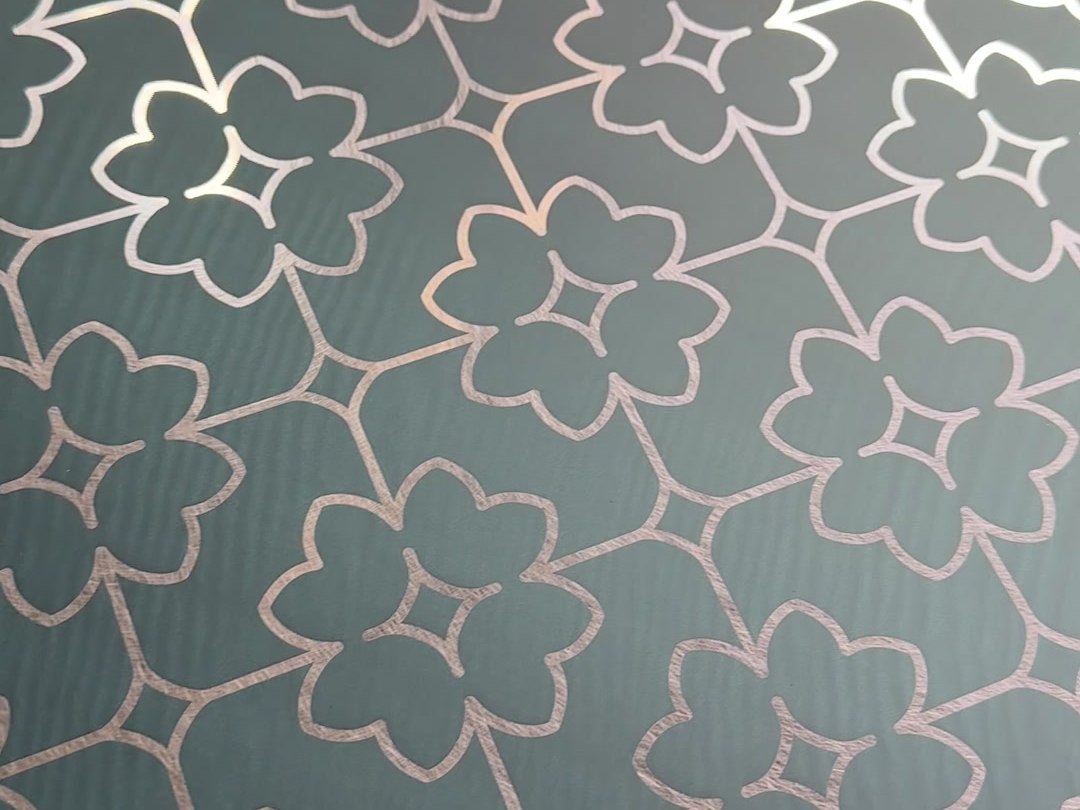 A floral etched pattern repeated across a full stainless steel sheet before the sheet is cut to panel size