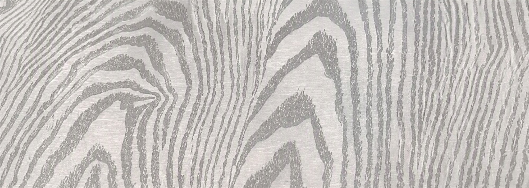 A close detail of the silver-grey wood-grain print in a printed stainless steel sheet