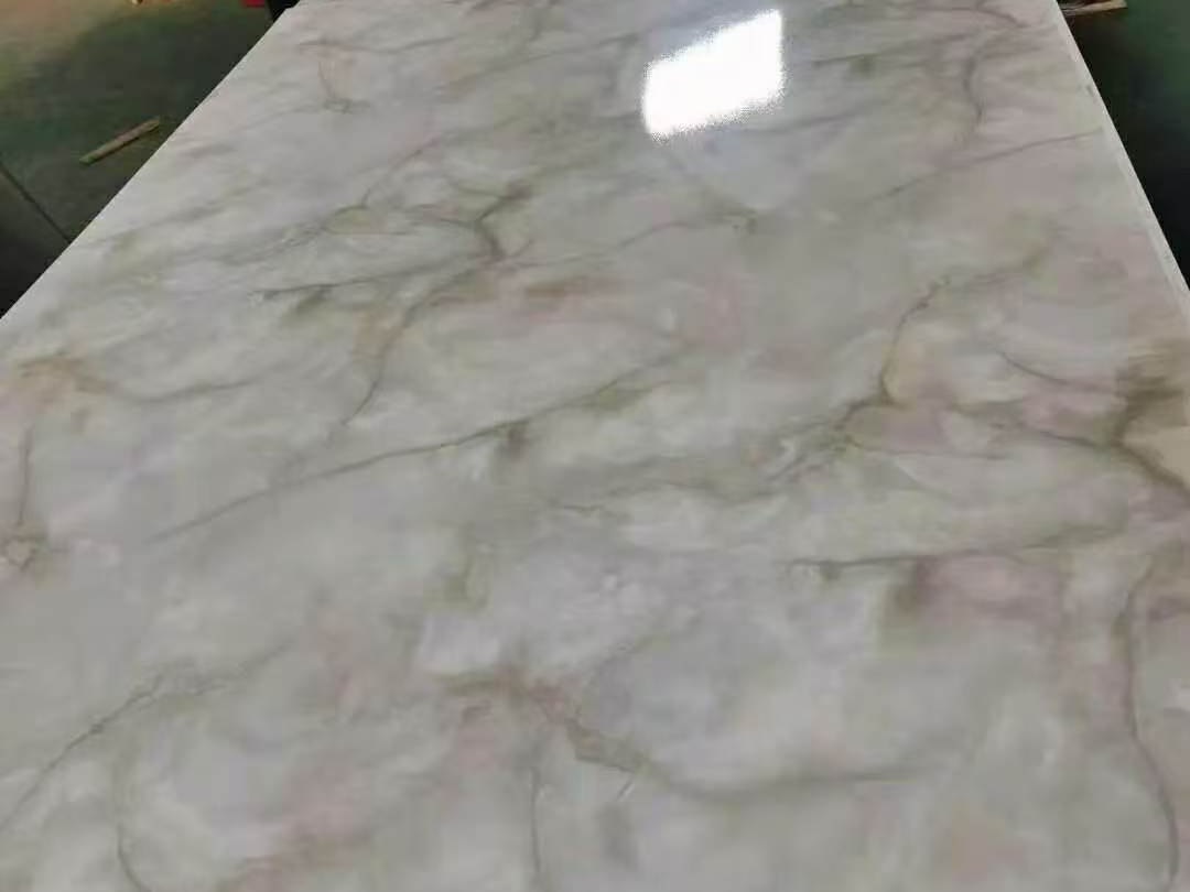 A printed stainless steel sheet carrying a marble-effect graphic, seen as a full plate